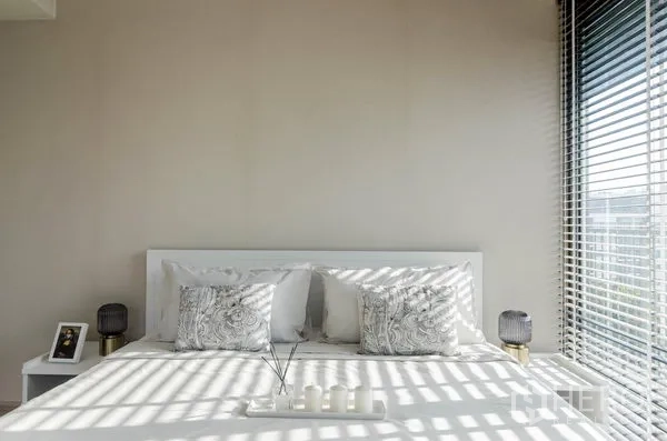 คอนโด ให้เช่าในWatthana, Bangkok - ห้องนอนสว่าง เตียงสีขาว หมอนลาย และหน้าต่างมุมห้องมองเห็นวิวเมือง