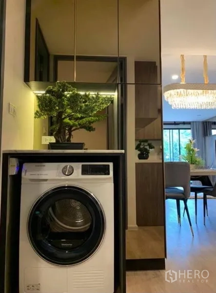 คอนโด ให้เช่าในPathum Wan, Bangkok - เครื่องซักผ้าแบบฝาหน้าในตู้บิวท์อิน หน้าบานกระจก มองเห็นโคมระย้าบริเวณทานอาหาร