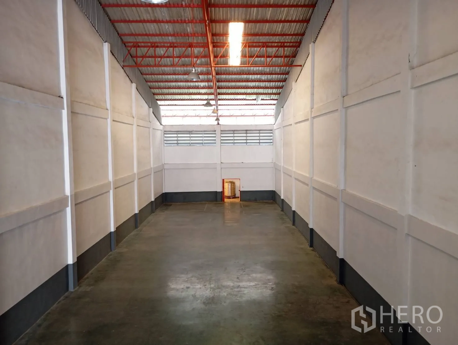 Warehouse for rent in Bang Phli, Samut Prakan - Long warehouse bay with concrete floor, tall roof and industrial lights.