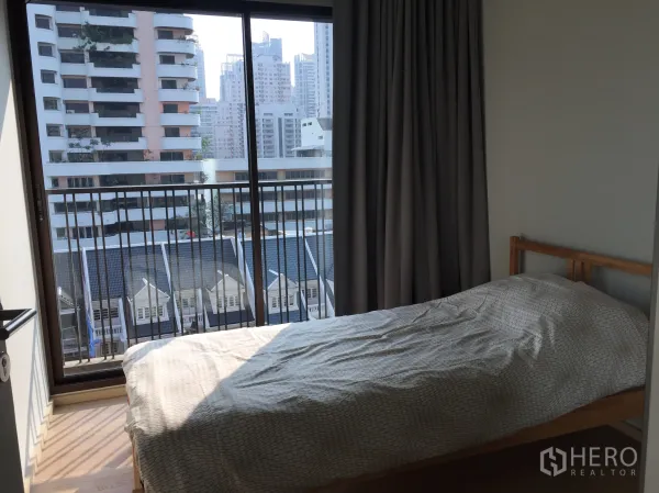 คอนโด ให้เช่าในBangkok - ห้องนอนรับแสงธรรมชาติ เตียงเดี่ยว ประตูกระจกบานเลื่อนเปิดสู่ระเบียงวิวเมือง