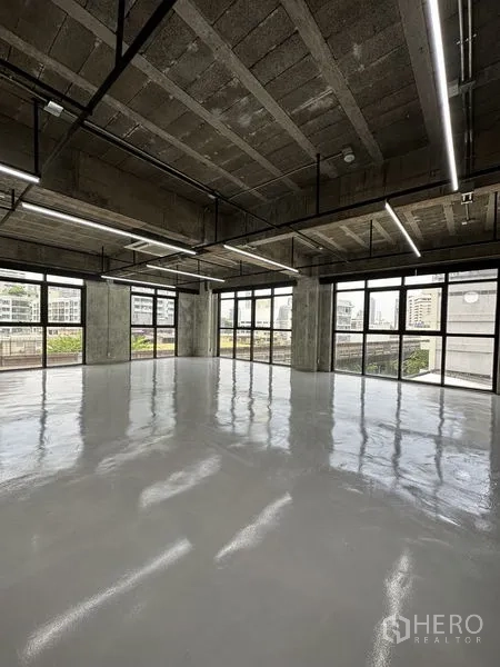 Office Space for rent in Khlong Toei, Bangkok - Bright shell office with polished epoxy floor, exposed concrete ceiling, linear LED lighting and floor-to-ceiling windows with city views near BTS Phrom Phong.