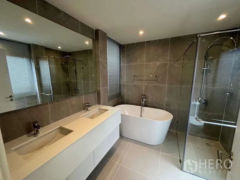 Townhouse for rent or sale in Don Mueang, Bangkok - Luxury bathroom with double vanity, freestanding bathtub and glass-enclosed shower.