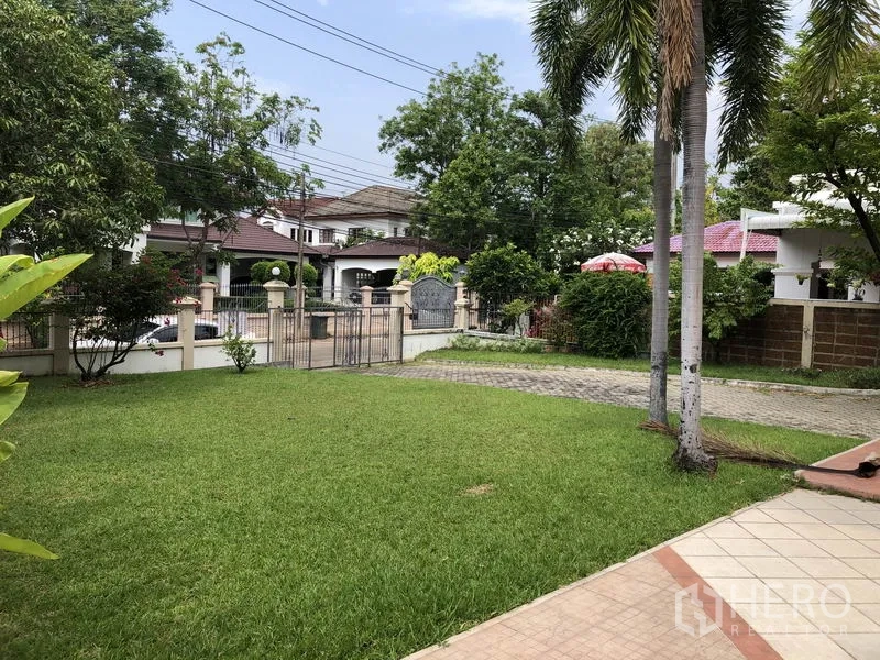 独立式住宅 出租 - 绿草坪与棕榈树，铺装车道及带门禁的庭院入口。