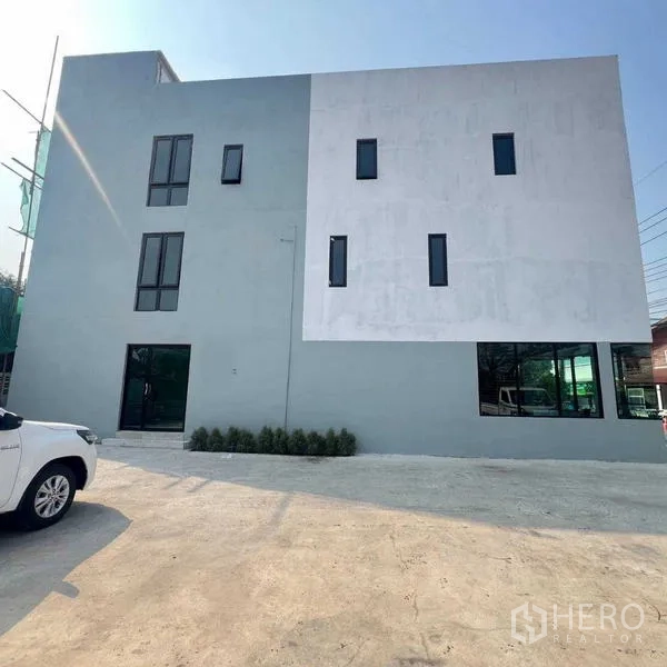 สำนักงานที่บ้าน ให้เช่าหรือขายในThanyaburi, Pathum Thani - ด้านข้างอาคารมินิมอล ช่องหน้าต่างยาว และลานจอดรถ