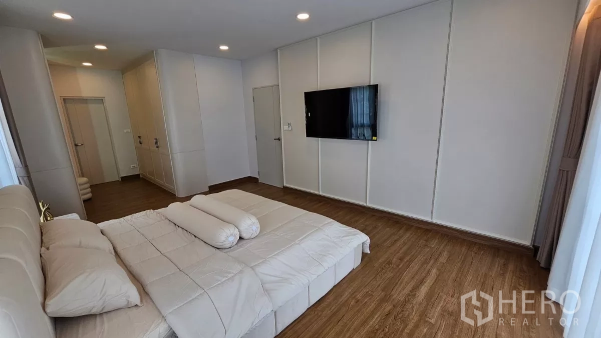 Detached House for rent or sale in Bang Phli, Samut Prakan - Master bedroom wall with mounted TV opposite the bed in a bright minimalist space.