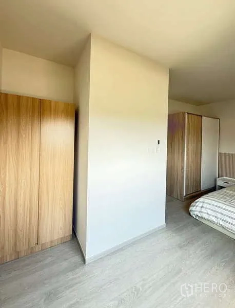 联排别墅 出租在Bang Phli, Samut Prakan - 卧室一角，两个衣柜与隔墙，浅色木地板。