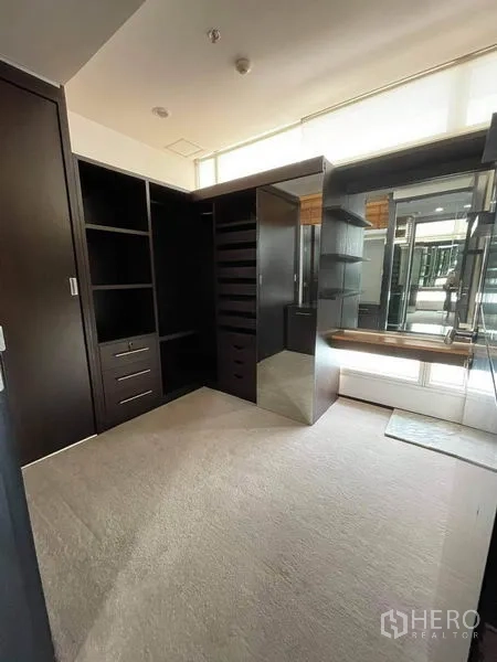 Condominium for rent or sale in Watthana, Bangkok - Walk-in closet with dark cabinetry, drawers and large mirrors.