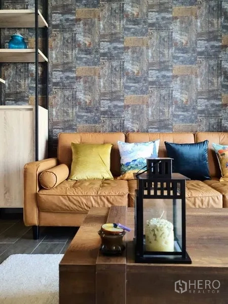 Condominium for rent or sale in Watthana, Bangkok - Leather sofa with colorful cushions beside a rustic feature wall and wooden coffee table.