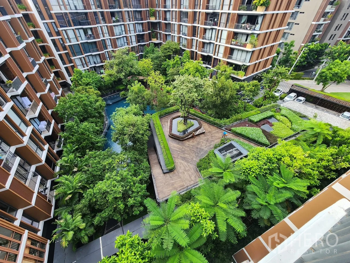 Condominium for rent in Watthana, Bangkok - Top-down view of the central garden courtyard with pathways, trees, and a lagoon-style pool.