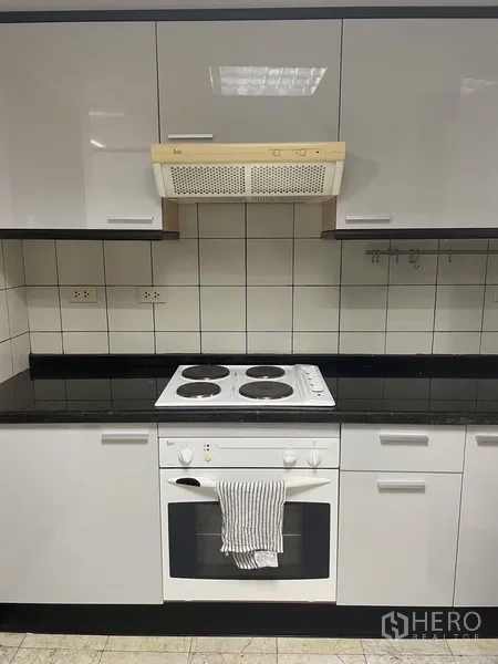 Condominium for rent or sale in Pathum Wan, Bangkok - Kitchen cooking zone with electric hob, oven, tiled backsplash and overhead extractor.