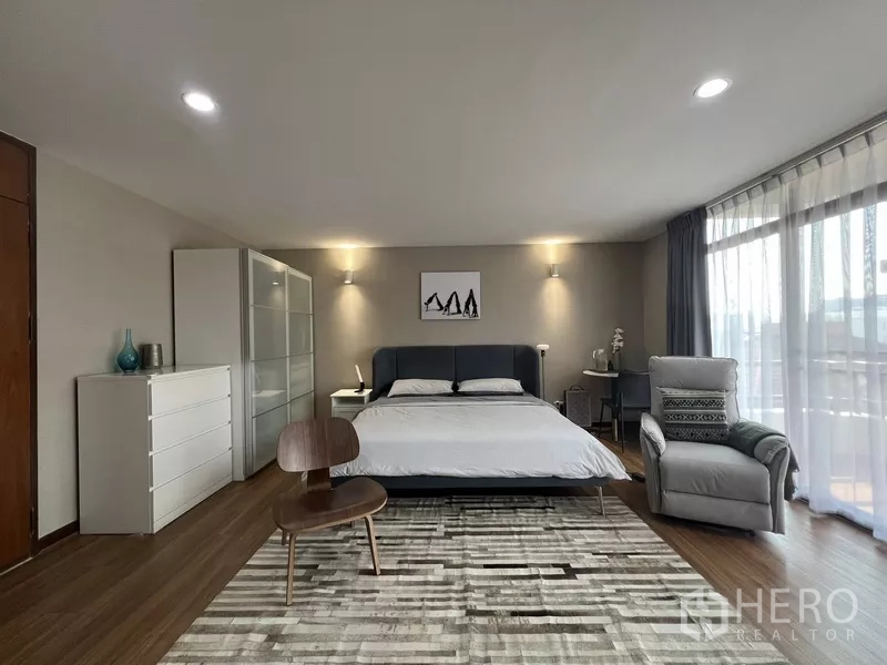 ทาวน์เฮาส์ ให้เช่าหรือขายในSuan Luang, Bangkok - ห้องนอนคิงไซส์ หัวเตียงสีเทา พรมลาย และผนังกระจกติดระเบียง