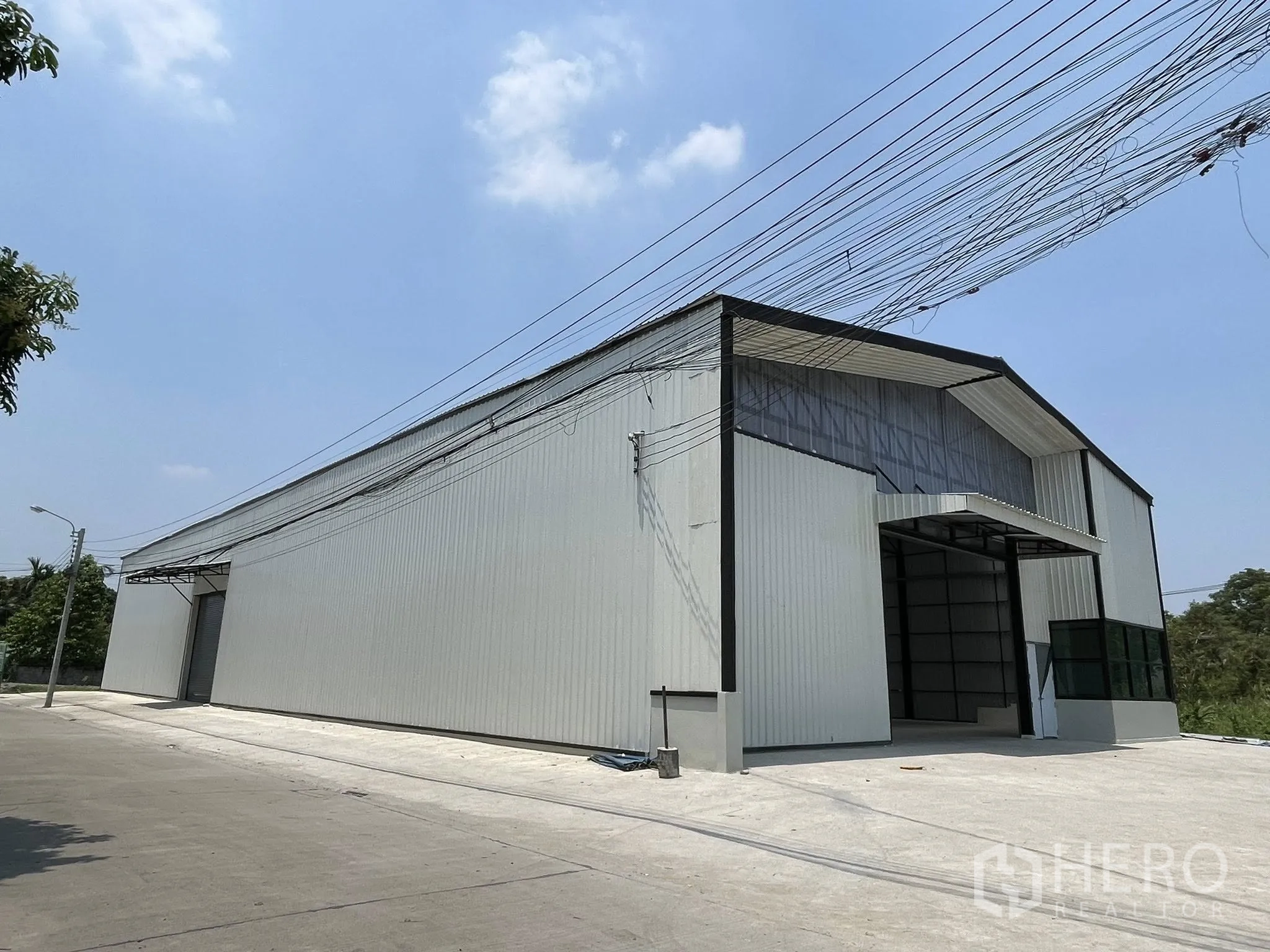 โกดัง for rent in Pak Kret, Nonthaburi - ภาพภายนอกโกดังโครงเหล็กหลังคาทรงจั่ว พร้อมลานคอนกรีตหน้าอาคาร