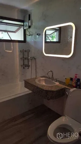 Detached House for rent in Bang Phli, Samut Prakan - Bathroom with illuminated mirror, marble walls, bathtub and modern fixtures.