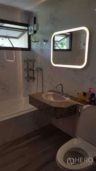Detached House for rent in Bang Phli, Samut Prakan - Bathroom with illuminated mirror, marble walls, bathtub and modern fixtures.