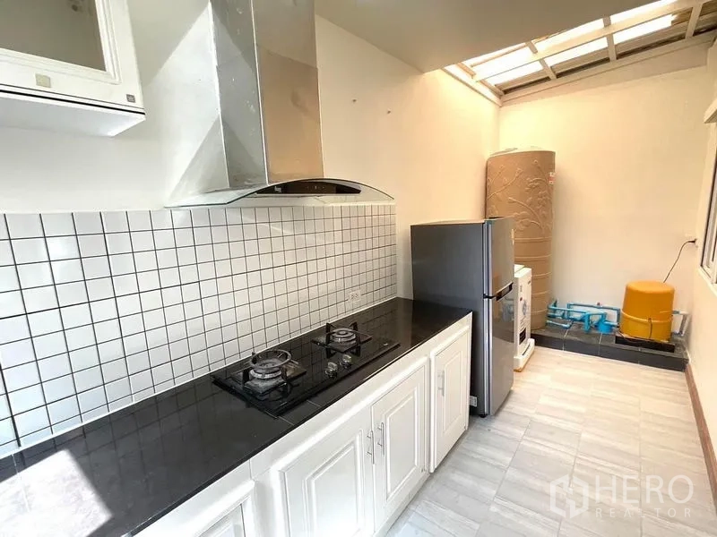 Townhouse for rent in Bang Phli, Samut Prakan - Back kitchen with black granite countertop, two-burner gas stove, hood and skylight.