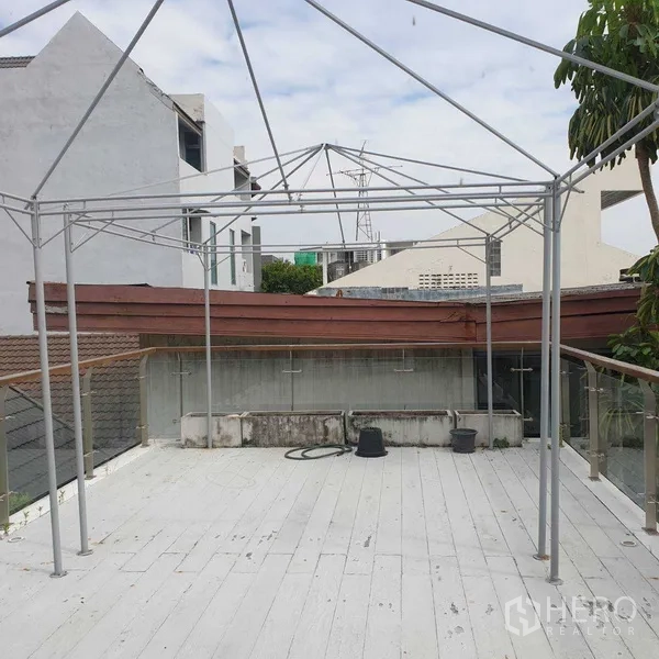Detached House for rent in Watthana, Bangkok - Rooftop terrace with metal pergola frame and glass railing overlooking surrounding rooftops.