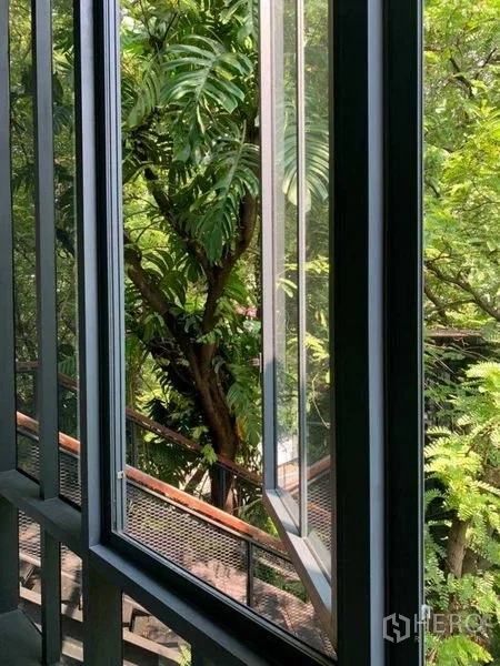 Office Space for rent in Khlong Toei, Bangkok - Open casement window overlooking lush green trees and an exterior walkway.