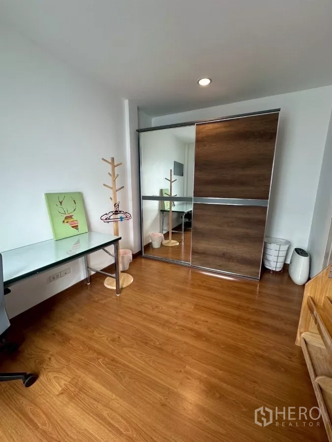 Townhouse for rent in Chom Thong, Bangkok - Bedroom view showing large sliding-door wardrobe and wood floors.