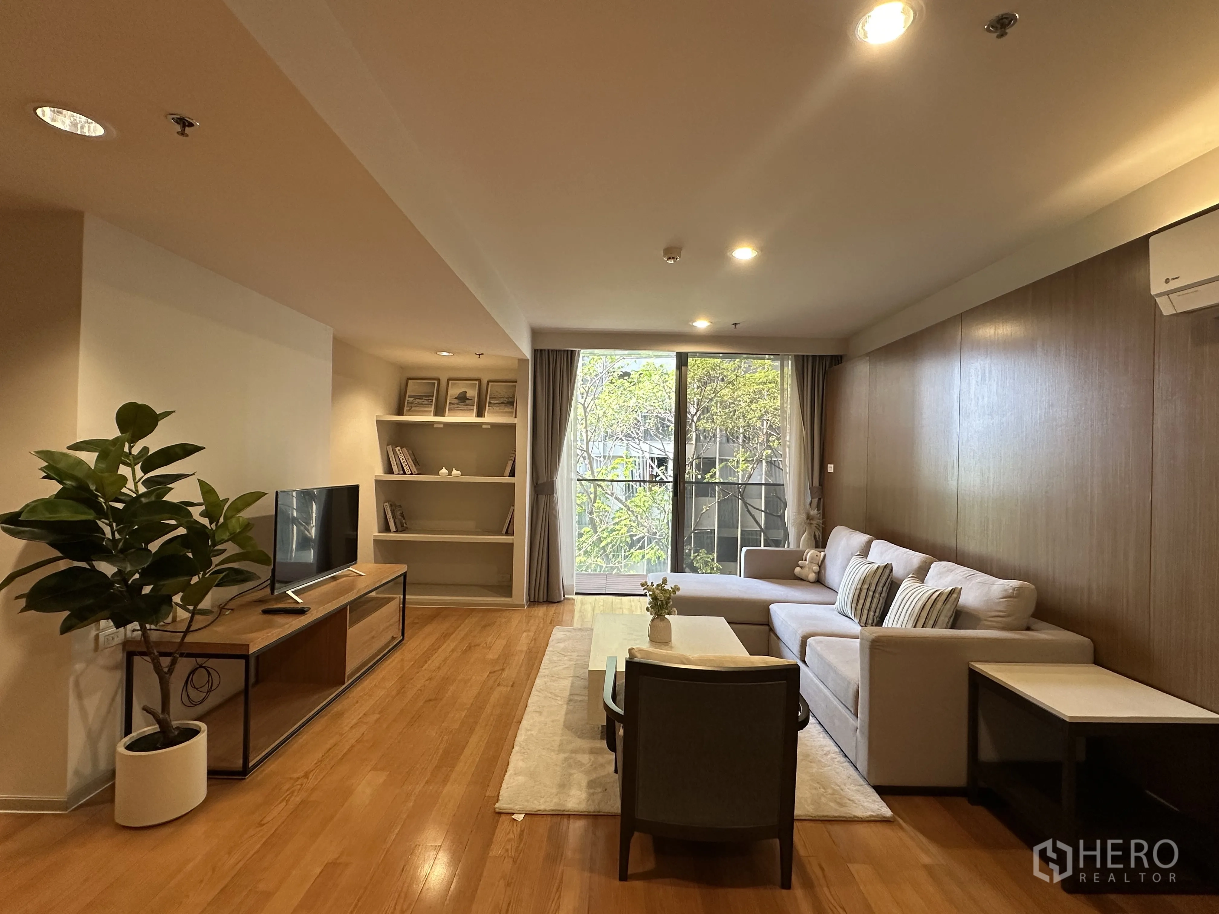 คอนโด for rent in Khlong Toei, Bangkok - ห้องนั่งเล่นกว้างพร้อมโซฟาตัวแอล ทีวีคอนโซล และประตูออกสู่ระเบียง