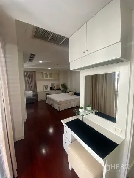 Condominium for rent in Pathum Wan, Bangkok - Dressing nook with mirror and stool leading to a spacious bedroom.