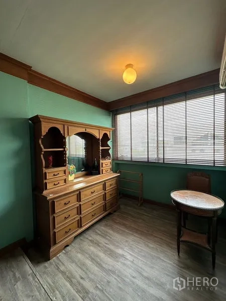 ทาวน์เฮาส์ ให้เช่าในKhlong Toei, Bangkok - ห้องอเนกประสงค์พร้อมหน้าต่างบานยาว ม่านมู่ลี่ และตู้ไม้โบราณกับโต๊ะเล็ก