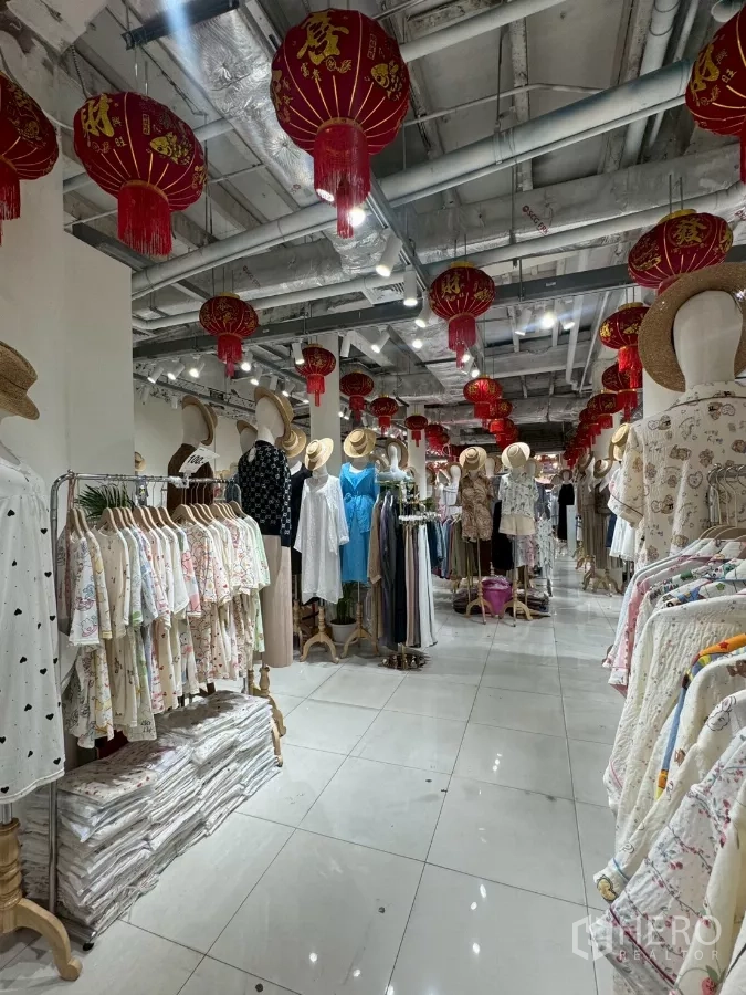 Shophouse for rent in Samphanthawong, Bangkok - Retail floor lined with clothing racks under red lanterns and exposed ducting.