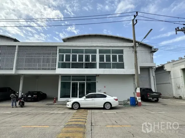 โรงงาน ให้เช่าในKhlong Luang, Pathum Thani - ด้านหน้าโรงงานสองชั้นพร้อมสำนักงานกระจก ประตูม้วน และที่จอดรถ ในโครงการที่มีความปลอดภัย