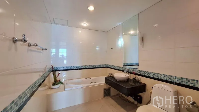 Condominium for rent in Khlong Toei, Bangkok - Bathroom with mosaic-tiled walk-in shower, toilet, and modern fixtures.