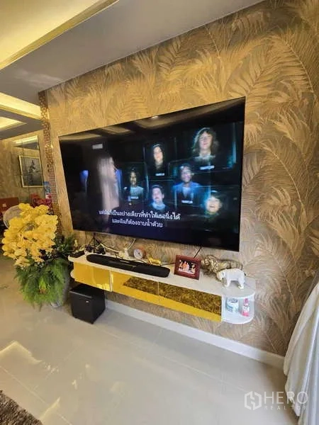 Detached House for rent in Thanyaburi, Pathum Thani - Living room feature wall with large wall-mounted TV, floating console and decorative plants.