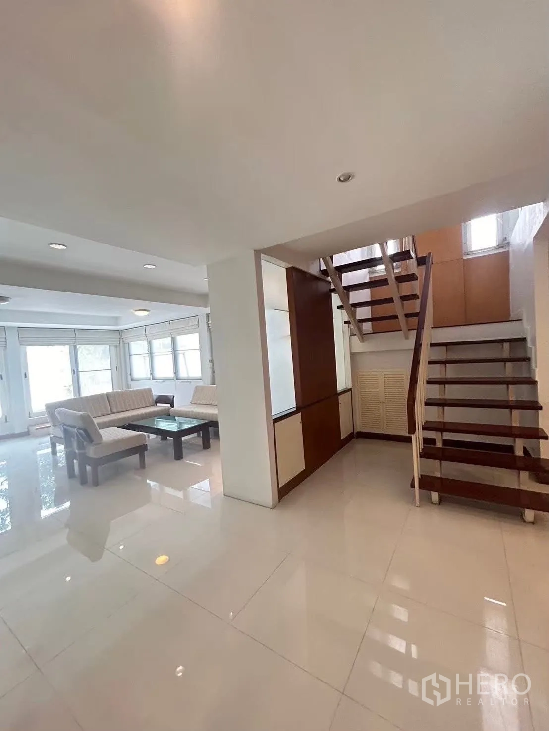 Detached House for rent in Suan Luang, Bangkok - Open‑plan lounge with stairs and seating on polished white tiles.