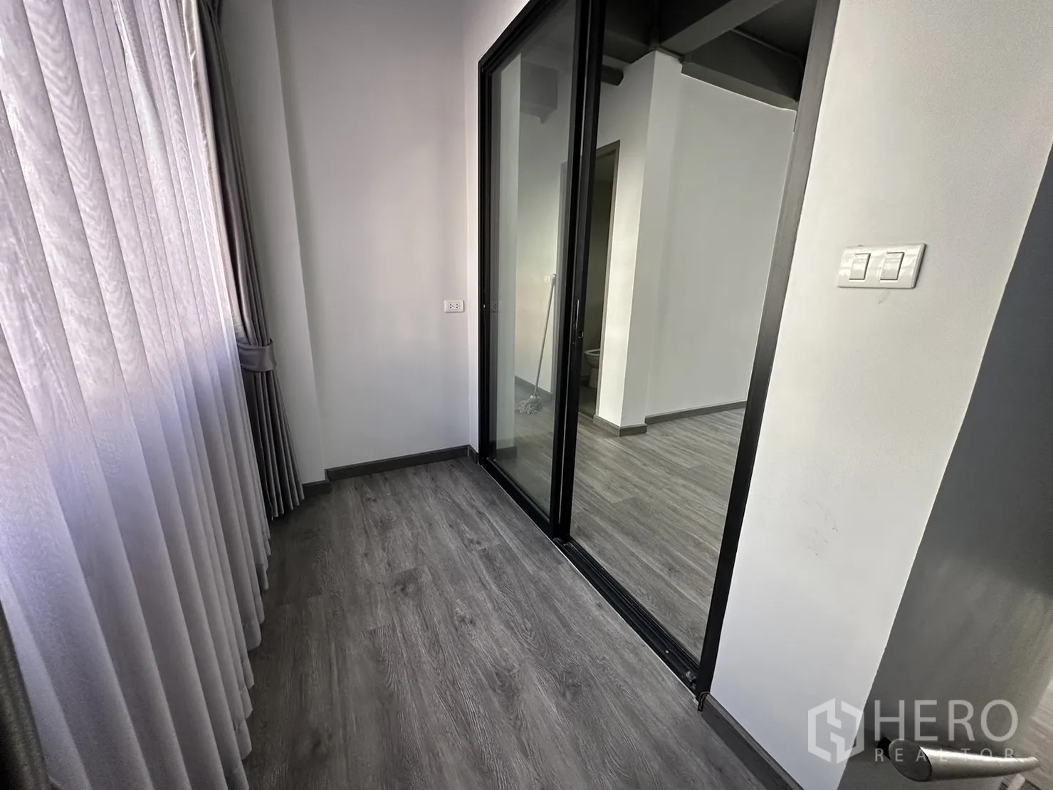 带办公室的家 出租或出售在Suan Luang, Bangkok - 带推拉玻璃门与高帘的小走廊，通向室内空间。