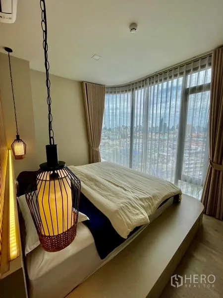 คอนโด ขาย - ห้องนอนมุมอาคาร กระจกเต็มบาน ผ้าม่านโปร่ง มองเห็นวิวเมืองกว้าง