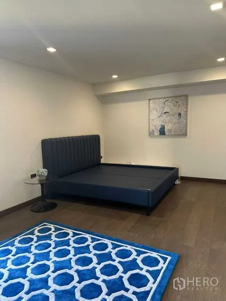 Detached House for rent in Suan Luang, Bangkok - Cozy bedroom with dark blue platform bed and patterned rug.