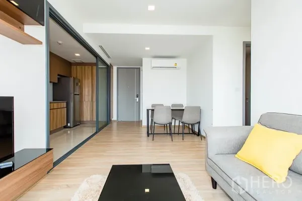 Condominium for rent in Watthana, Bangkok - View from lounge to dining and a separate kitchen behind glass sliding doors with wood cabinetry and full appliances.