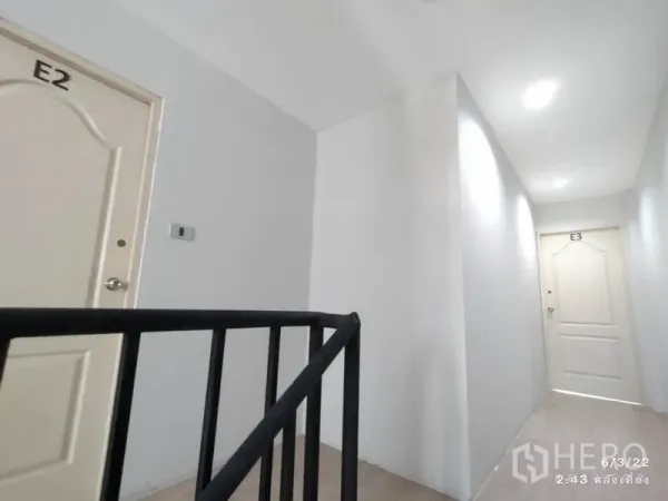 零售空间 出租在Phaya Thai, Bangkok - 干净走廊，白色E2与E3房门，旁有黑色金属楼梯扶手。