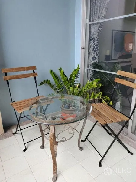 公寓 出租在Khlong Toei, Bangkok - 阳台休闲区，玻璃圆桌、两把木椅与绿植。