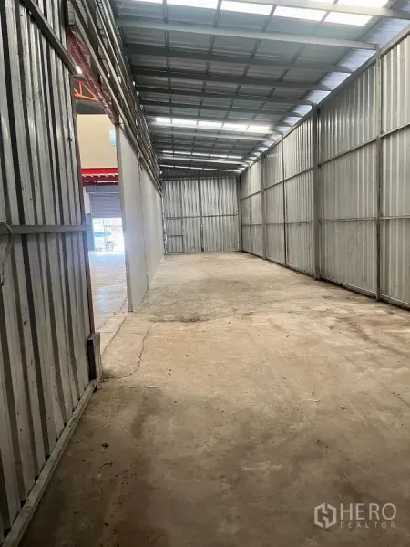 Warehouse for rent in Lat Lum Kaeo, Pathum Thani - Covered storage lane with metal sheet walls and skylight roof panels.
