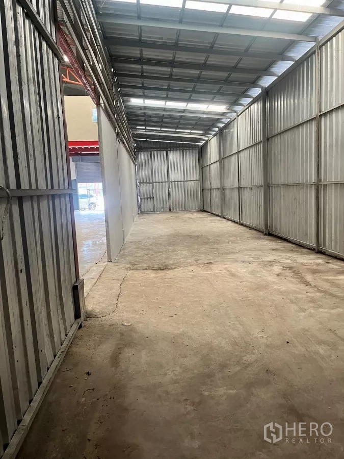 Warehouse for rent in Lat Lum Kaeo, Pathum Thani - Covered storage lane with metal sheet walls and skylight roof panels.