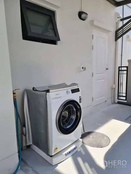 Detached House for rent in Samut Prakan - Outdoor laundry area with front-load washing machine, hose tap and utility door.