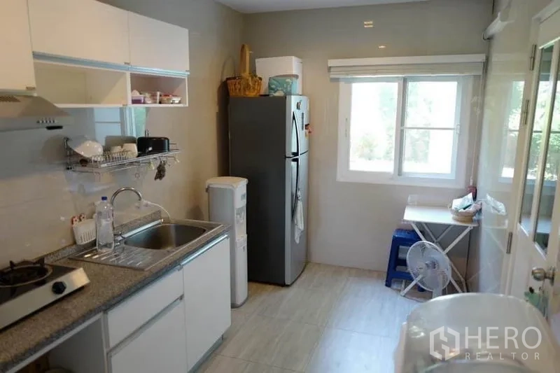 Detached House for sale in Pak Kret, Nonthaburi - Compact kitchen with window, sink, stovetop and double-door refrigerator.