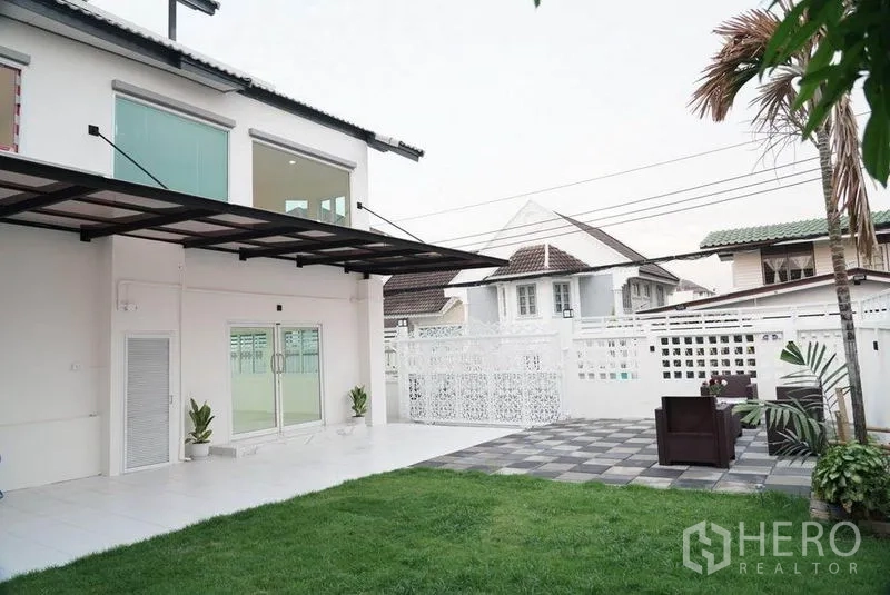 Detached House for sale in Bang Bon, Bangkok - Garden view of the house showing sliding doors, lawn and outdoor seating area.