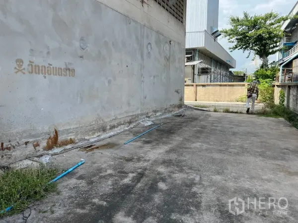 Warehouse for rent in Mueang Samut Prakan, Samut Prakan - Concrete side driveway along the warehouse wall providing truck access and ventilation blocks.