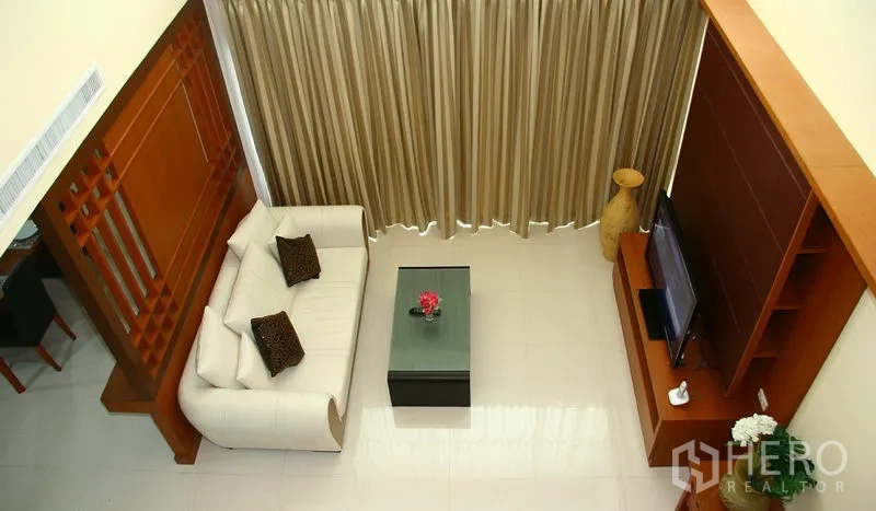Apartment for rent in Khlong Toei, Bangkok - Living room viewed from above with white sofa, TV cabinet and full-length curtains
