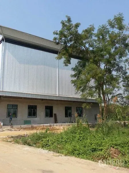 Land for rent or sale in Khlong Toei, Bangkok - Warehouse-style building with corrugated facade adjacent to the land plot.