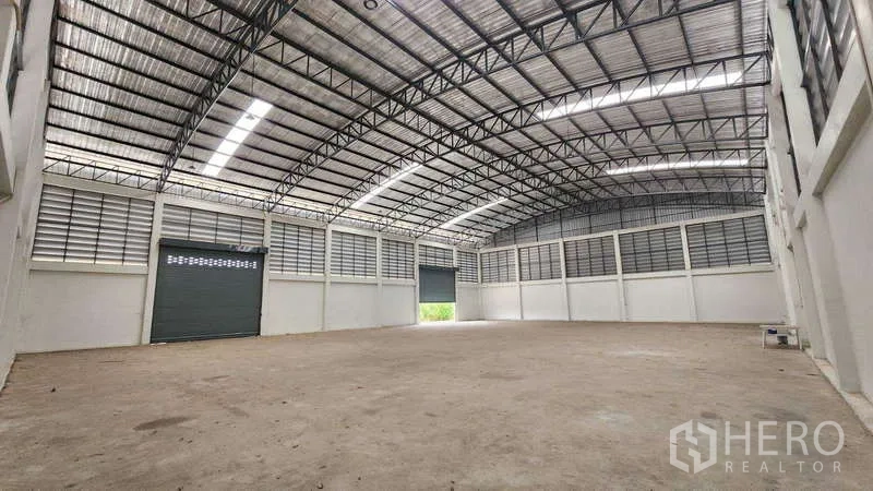 工厂 出租在Ban Phaeo, Samut Sakhon - 工厂内部空间宽敞，拱形钢结构屋顶，天窗采光、百叶通风与大型卷闸门。