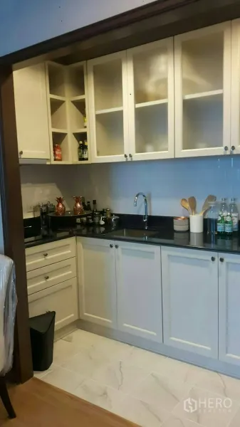 คอนโด ให้เช่าในPathum Wan, Bangkok - ครัวรูปตัวแอล ตู้บานกระจกสีขาว ท็อปหินสีดำและอ่างล้างจาน