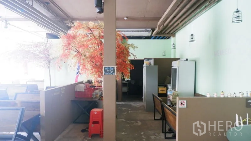 零售空间 出租在Watthana, Bangkok - 开放式零售空间，设有卡座、吊灯、裸露管线与装饰树景。