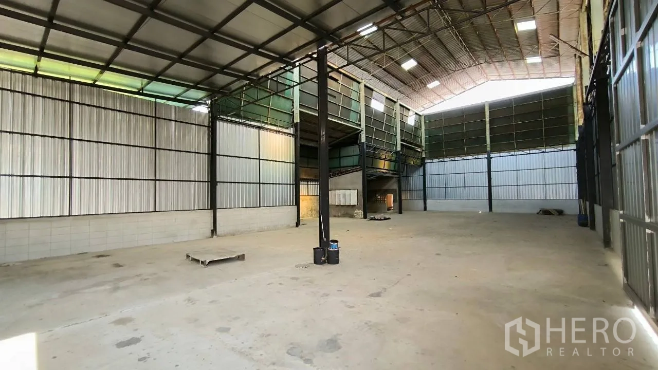 Factory for rent in Mueang Samut Prakan, Samut Prakan - Open warehouse space with metal cladding, mezzanine platform, and bright roof panels.