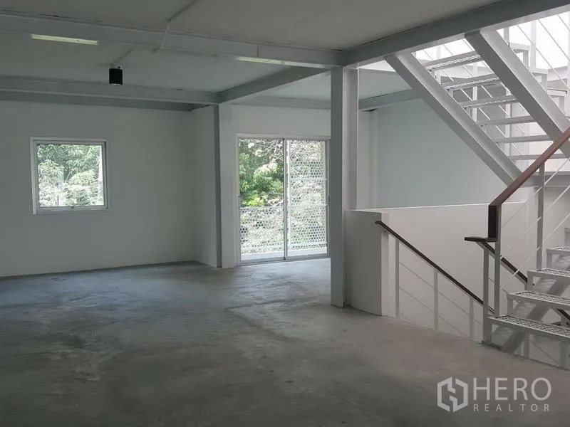 Home Office for rent in Khlong Toei, Bangkok - Spacious level with a steel staircase and sliding glass doors overlooking greenery.