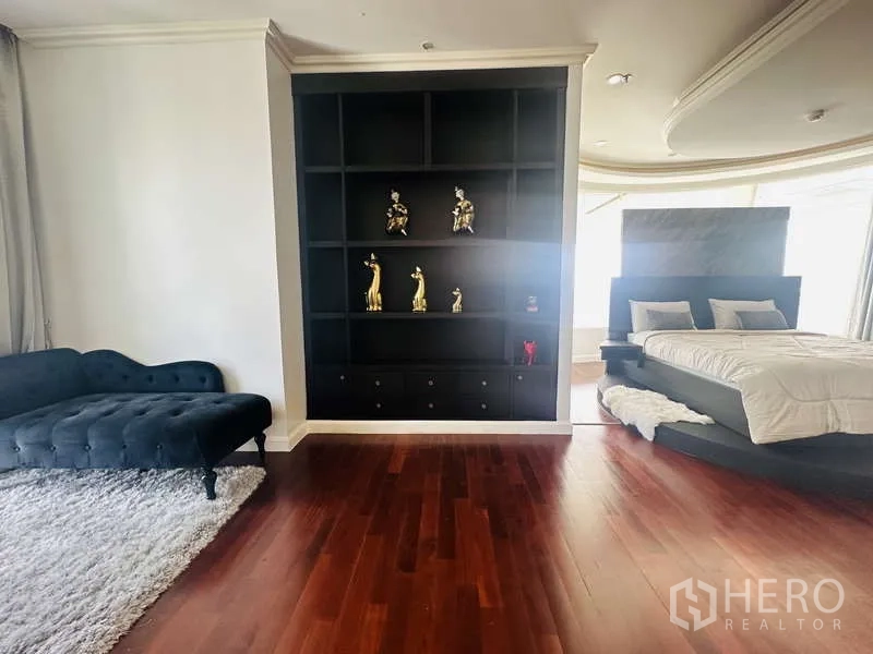 คอนโด ให้เช่าหรือขายในKhlong Toei, Bangkok - ส่วนนั่งเล่นของห้องมาสเตอร์ ชั้นวางโชว์บิลท์อิน เดย์เบด และเตียงบนแท่นพื้นไม้เงา